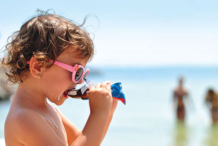 A child is eating ice cream at the beach